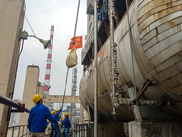 5月10日中午，在動力車間三期工藝除氧器地面，黨員突擊隊隊員用滑輪往工藝除氧器平臺運送鋼絲網(wǎng)，用以纏繞新填料.jpg